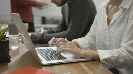 Horizontal video: A woman working on a laptop gets assistance by a co worker seated besides her 3205618. Duration: 21 seconds. Resolution: 1920x1080