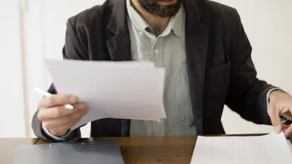 Horizontal video: Man holding documents while looking at camera 8439249. Duration: 13 seconds. Resolution: 3840x2160