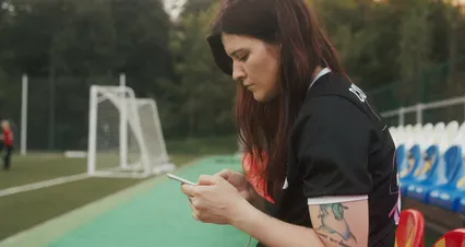 Horizontal video: Female football player using her phone while on the bench 9501821. Duration: 16 seconds. Resolution: 4096x2160