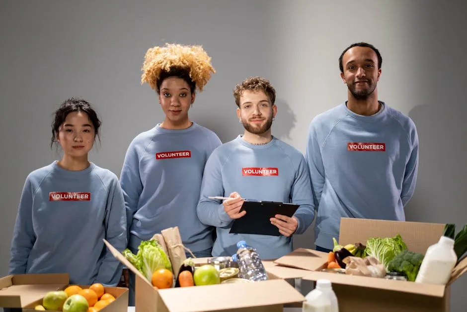 Volunteers in Blue Long Sweater Standing in Front of Brown Boxes while Looking at the Camera