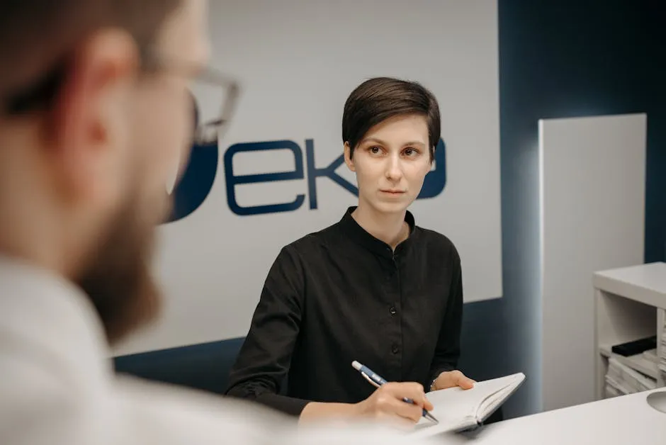 Woman at Reception Desk Writing Patient Data in a Notebook