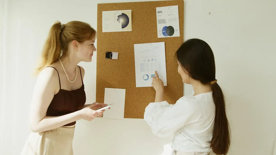 A Woman in White Long Sleeve Shirt Pointing a Graph Posted on Corkboard