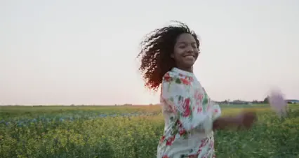 Horizontal video: A smiling woman in a flowery dress running in a meadow 10544168. Duration: 23 seconds. Resolution: 4096x2160