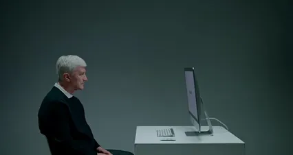 Horizontal video: Side view of an elderly man sitting in front of a computer 9832475. Duration: 20 seconds. Resolution: 4096x2160