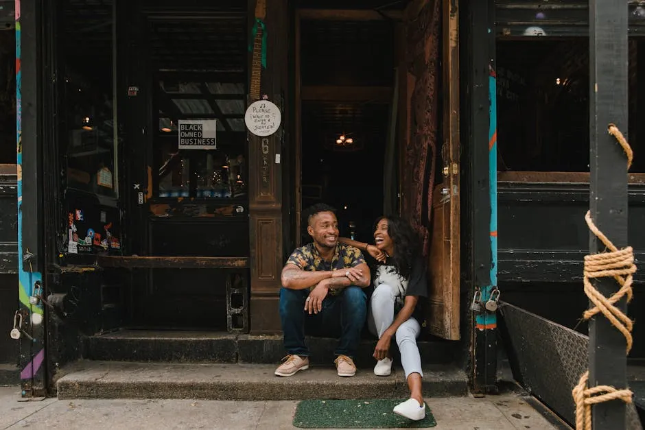 Portrait of Smiling Owners Sitting in Front of Cafe