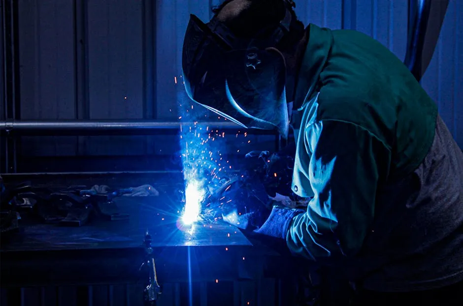 Blue Toned Image of a Man Welding in Protective Clothing and Goggles