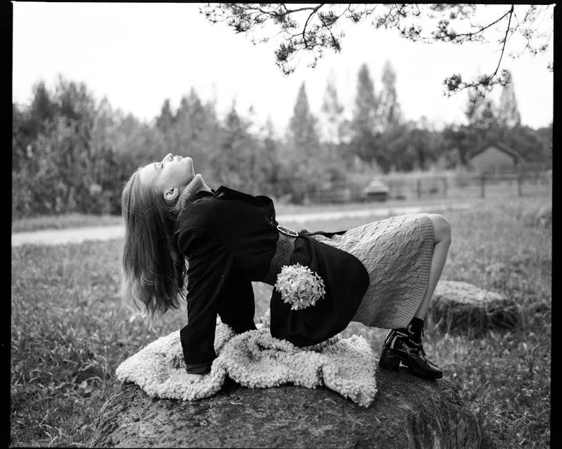 Black and White Photo of Woman Sitting on Rock Leaning Back