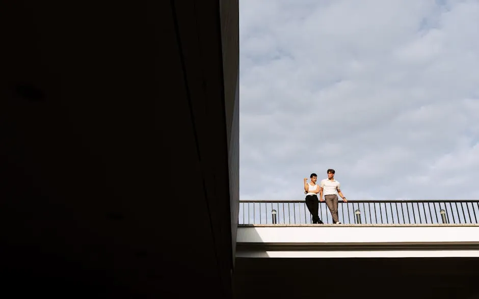 Couple Standing on Bridge Holding onto Railing under Cloudy Sky