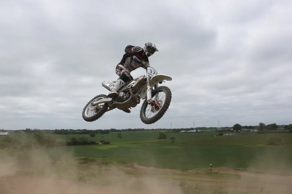 Man Riding Moto Cross Bike Doing Tricks Mid Air Under Cloudy Skies during Daytime