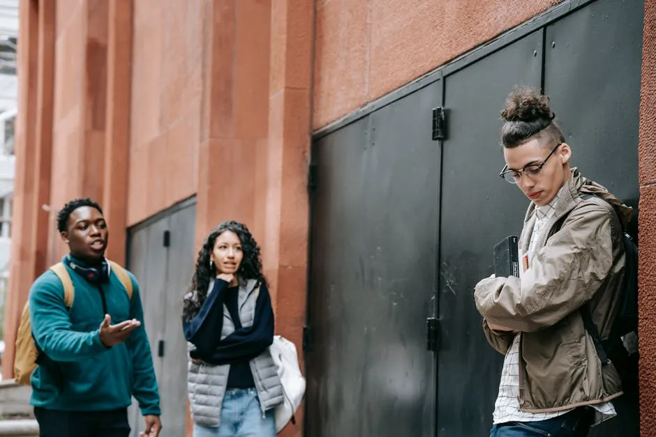 Bullied ethnic guy leaning on wall near rebellious multiracial classmates