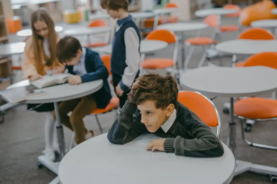 A Boy Sitting Alone Away From Fellow Students
