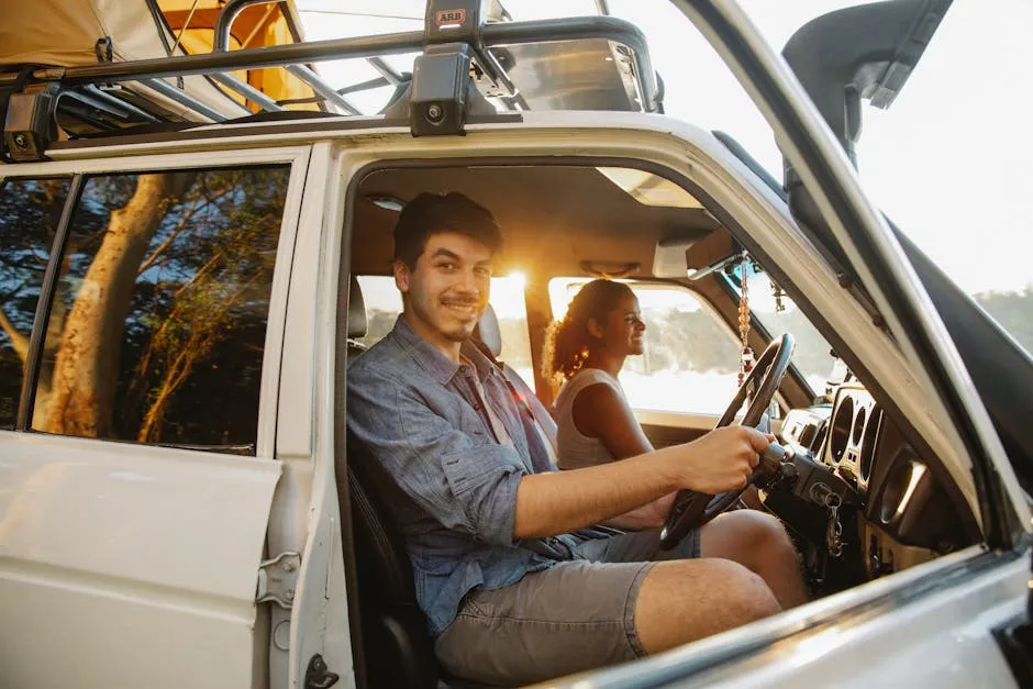 Side view of joyful young multiethnic male and female campers sitting in car with tent on top and smiling during trip at sunset