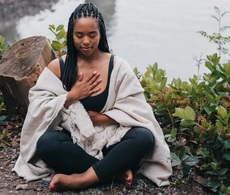 A woman practicing mindful meditation outdoors by the water, symbolizing wellness and relaxation.