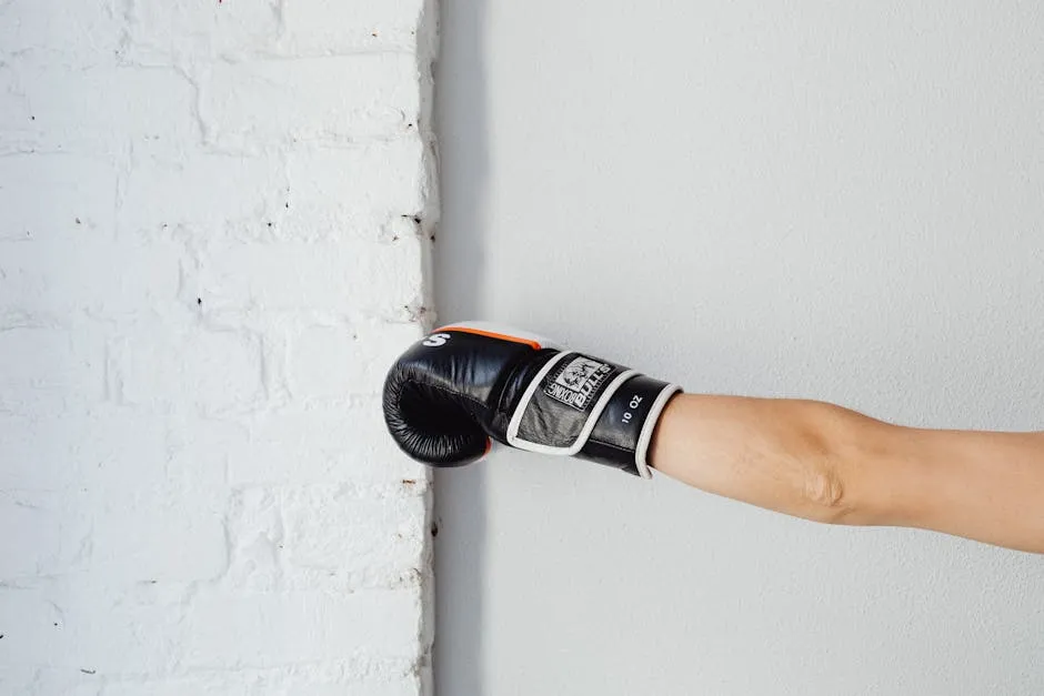 A boxing glove worn by a person punching a white brick wall, indoors with natural lighting.