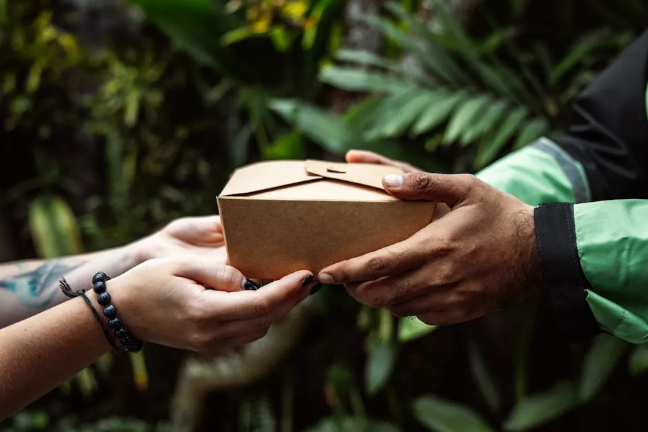 Close-up of hands exchanging a cardboard package in a lush green setting, representing eco-friendly delivery.