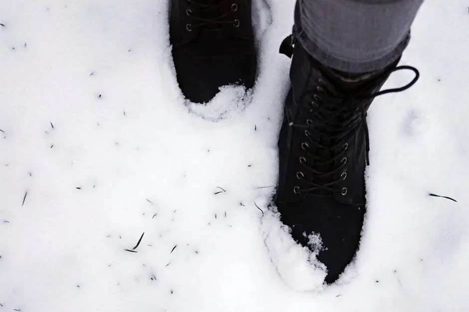 Black boots make a footprint in fresh snow, capturing a wintery scene outdoors.