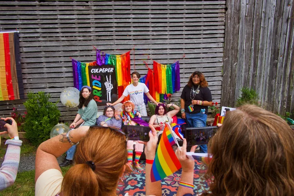 Group of diverse individuals celebrate Pride with colorful flags and joyful smiles outdoors.