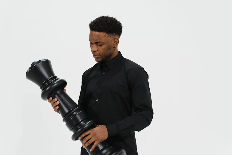 African American man holds a large king chess piece against a white background.