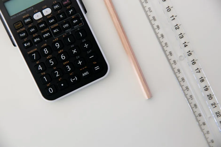 Top view of a calculator, ruler, and pencil arranged on a white surface.