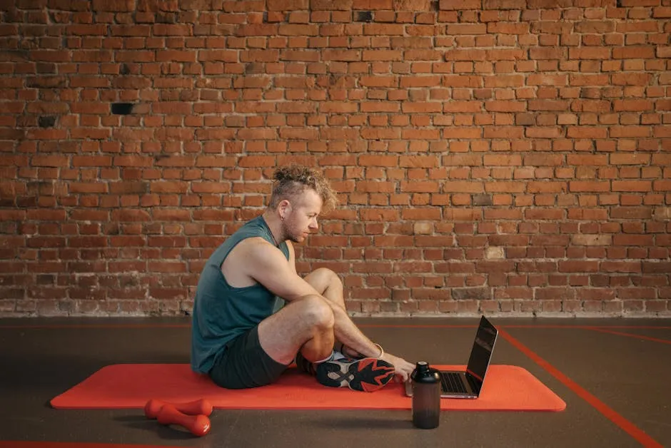 Man Sitting on Exercise Mat While Using Laptop