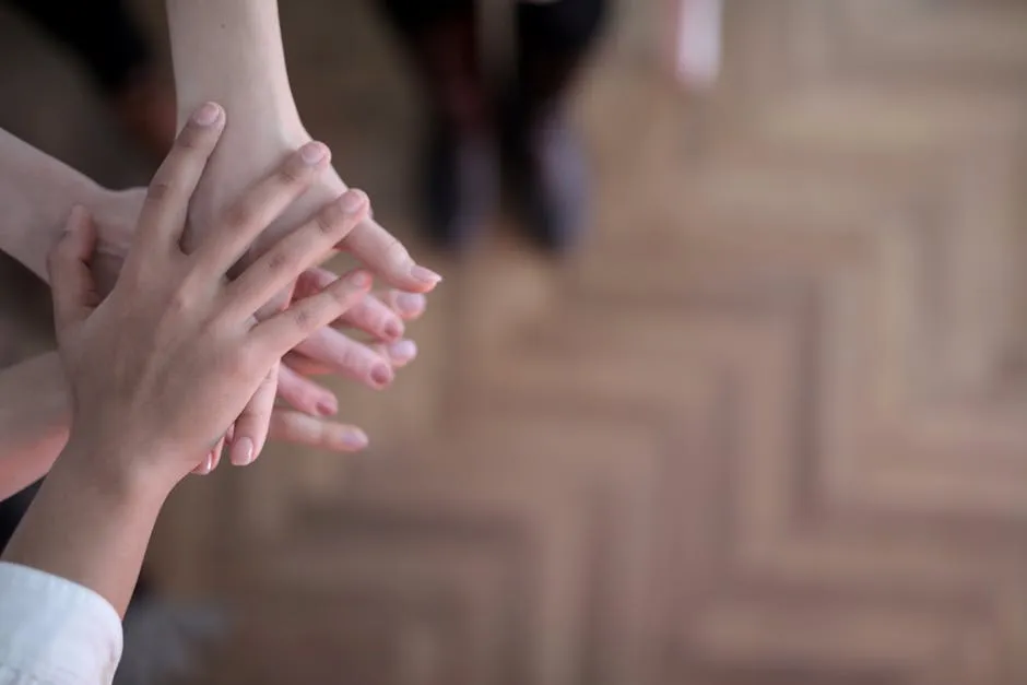 Hands stacked showing teamwork and unity from a top view indoors.